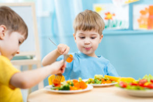 children eating vegetables in kindergarten or at home